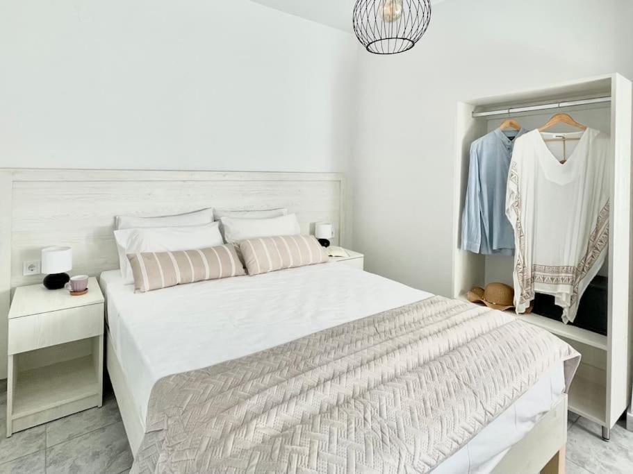a white bedroom with a large bed and a closet at Sunny Apt at Regina Apartments in Zakynthos Town