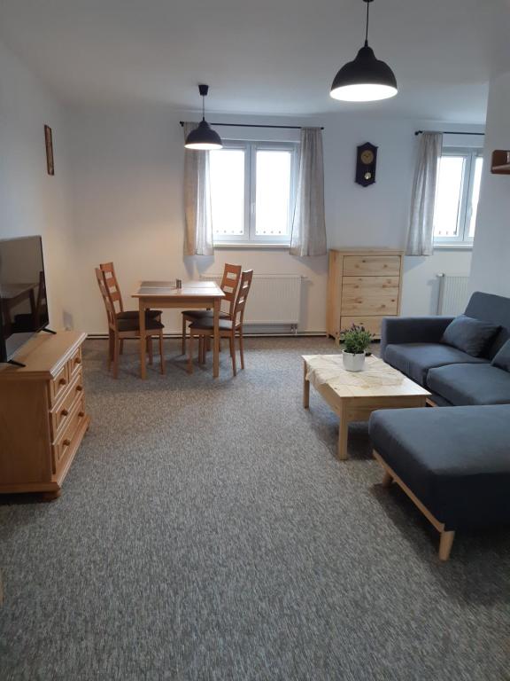 a living room with a blue couch and a table at Černá v Pošumaví Apartmán in Černá v Pošumaví
