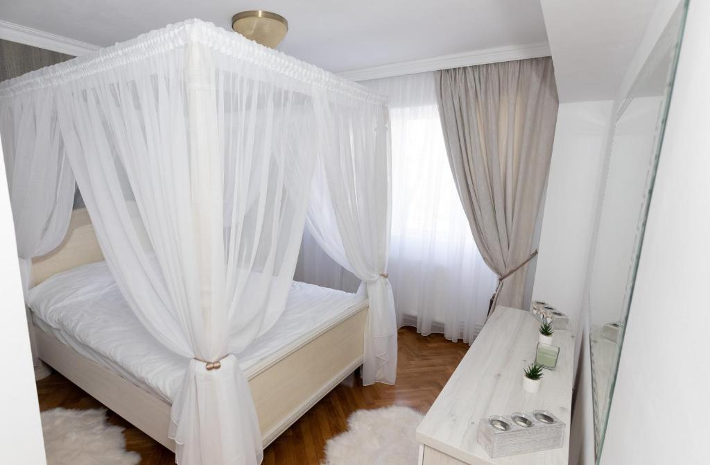 1 dormitorio con cama con dosel y cortinas blancas en ALPASIO RENTALS, en Galaţi