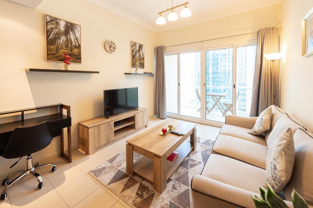 a living room with a couch and a tv at Elegant and spacious 1bed with 2 balconies in JLT - LAKV in Dubai