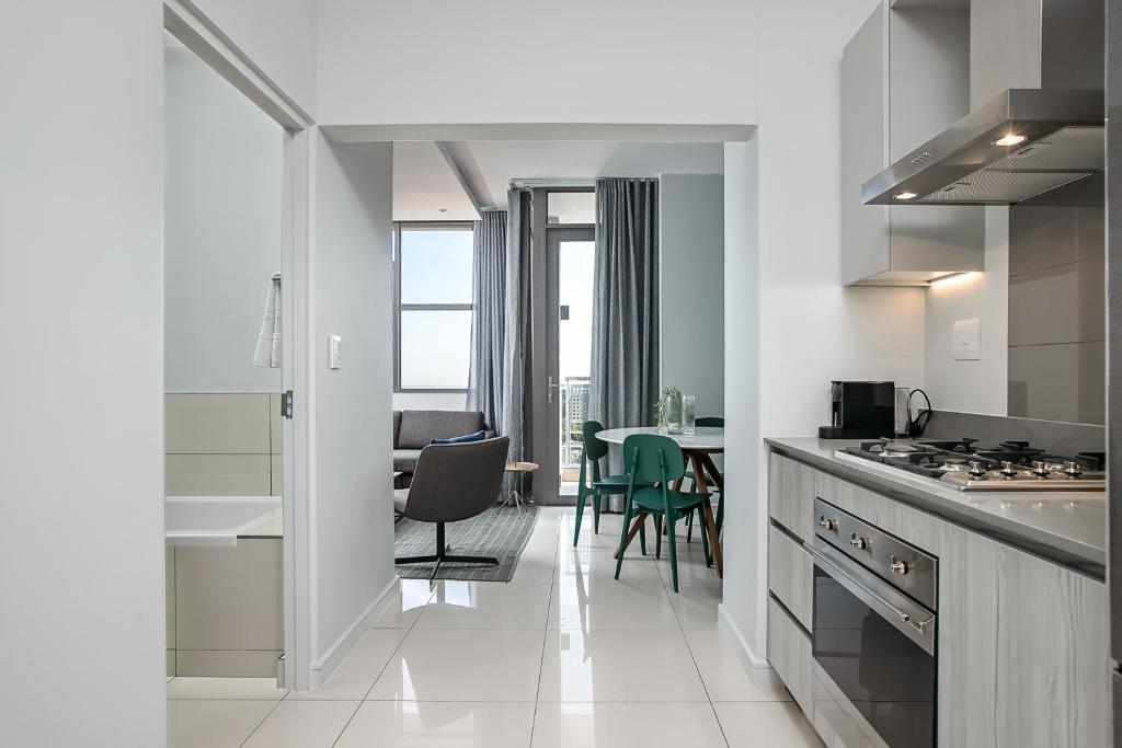 a white kitchen with a table and a dining room at The Median Serviced Apartment Collection in Johannesburg