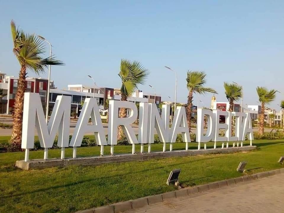 a large white sign in a park with palm trees at شالية مميز بقرية مارينا دلتا السياحية ol2o72ool82 in ‘Izbat Abū Sulayman