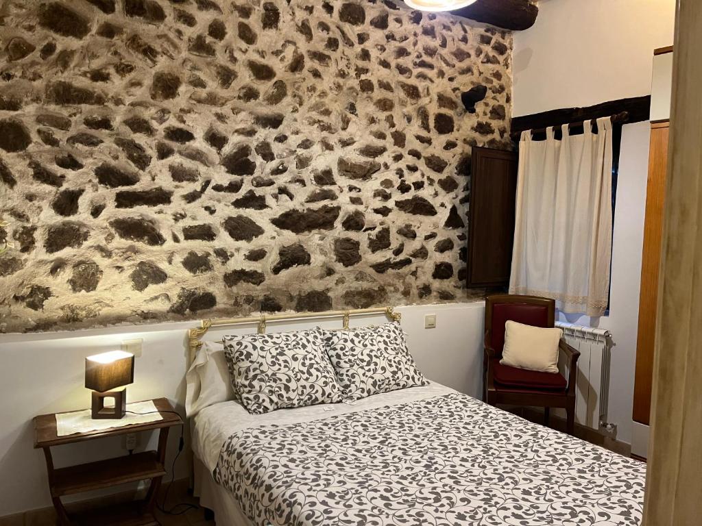 - une chambre avec un lit et un mur en pierre dans l'établissement Apartamento Puerta Grande, à Candelario