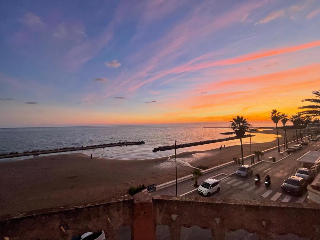 widok na plażę o zachodzie słońca z zaparkowanymi samochodami w obiekcie Mirage Rooms w Anzio