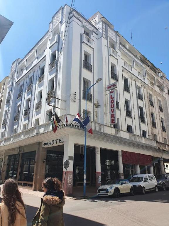 two women walking down a street in front of a building at HOTEL DU LOUVRE in Casablanca