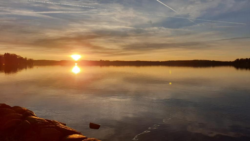 a sunset on a lake with the sun setting at Helle Souterrain Wohnung in Laufnähe zum Wörthsee in Wörthsee