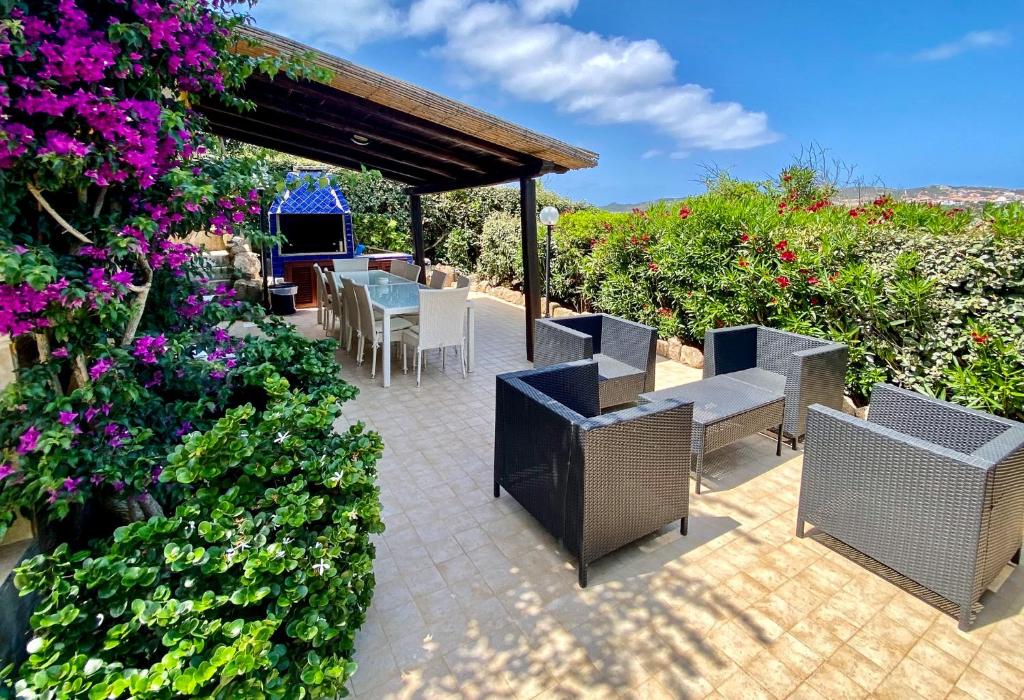 un patio con mesa, sillas y flores en Villa Oleandri en Santa Teresa Gallura
