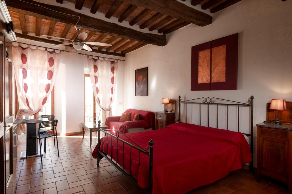 a bedroom with a red bed and a living room at Casa Aurora in Massa Marittima