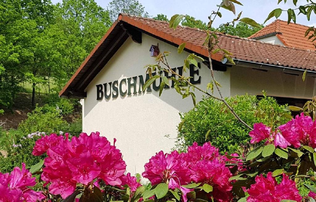 um sinal na lateral de um edifício com flores cor-de-rosa em Biohof Buschmühle em Königsfeld