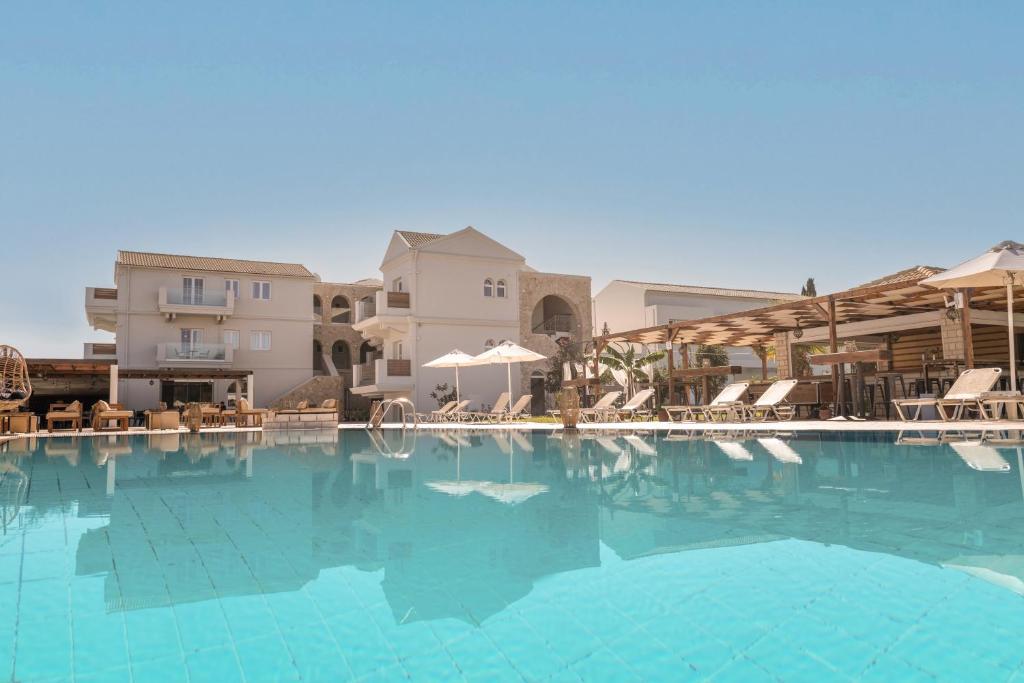 a large swimming pool with chairs and umbrellas at Ekati Mare Boutique Resort in Kavos