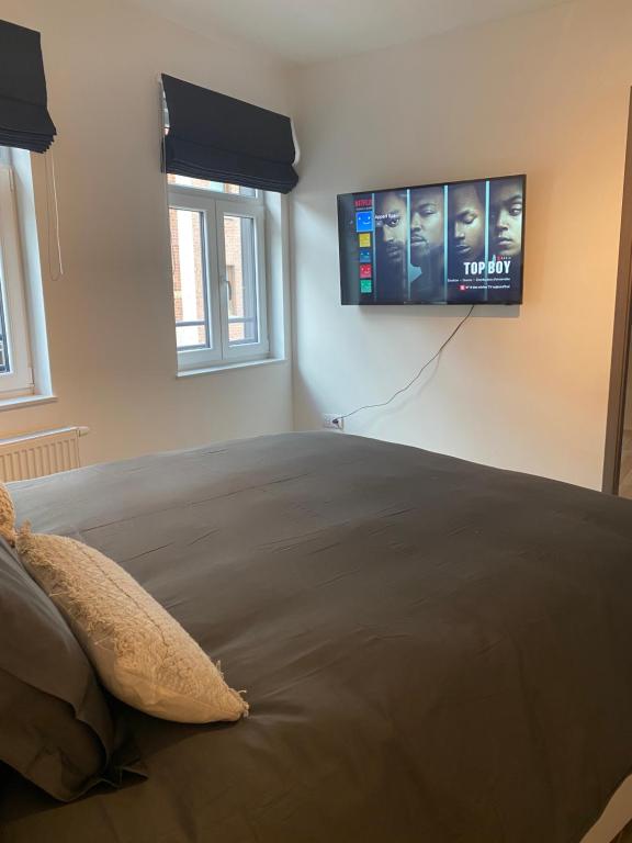 a bedroom with a bed with a television on the wall at New appartement centre de Spa avec parking privé in Spa