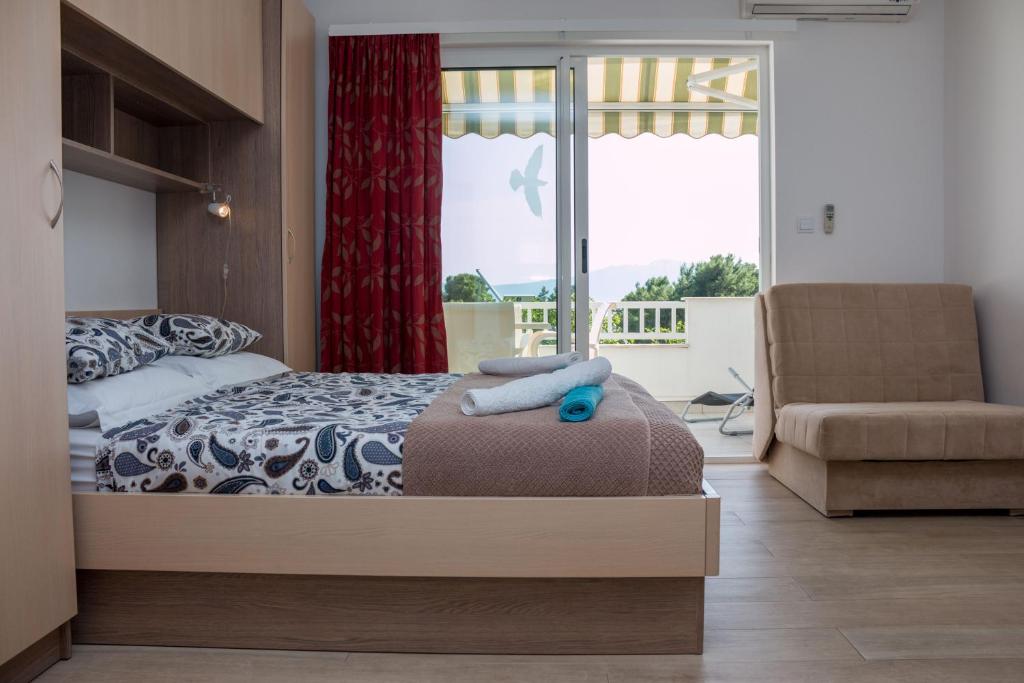 ein Schlafzimmer mit einem Bett, einem Stuhl und einem Fenster in der Unterkunft Apartment Bilalovic in Zaostrog