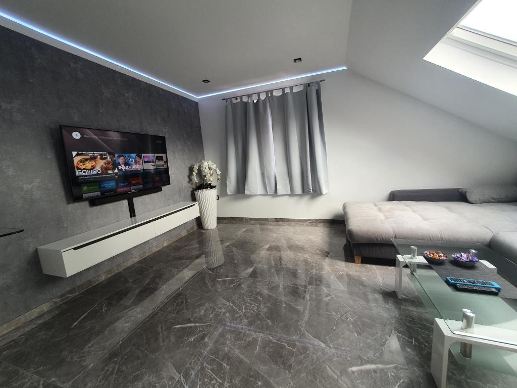 een woonkamer met een bank en een tv aan de muur bij New York City Apartment in Paderborn