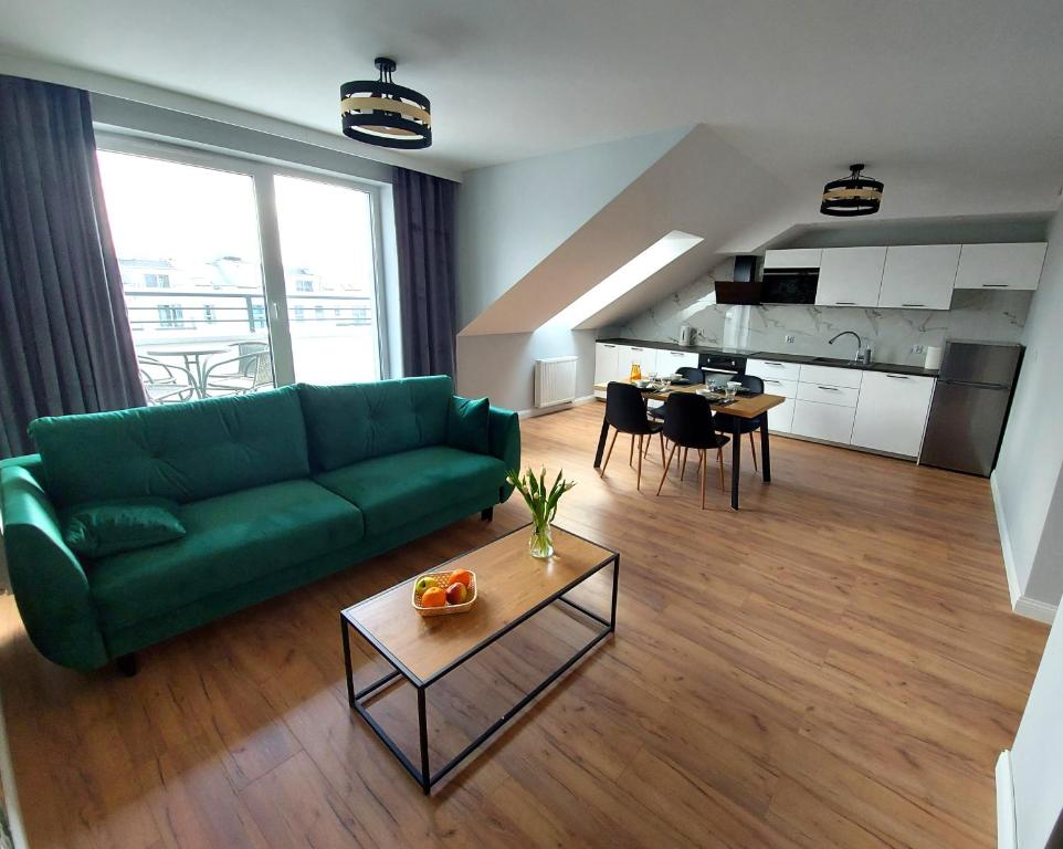 Marina Gdańsk في غدانسك: غرفة معيشة مع أريكة خضراء وطاولة