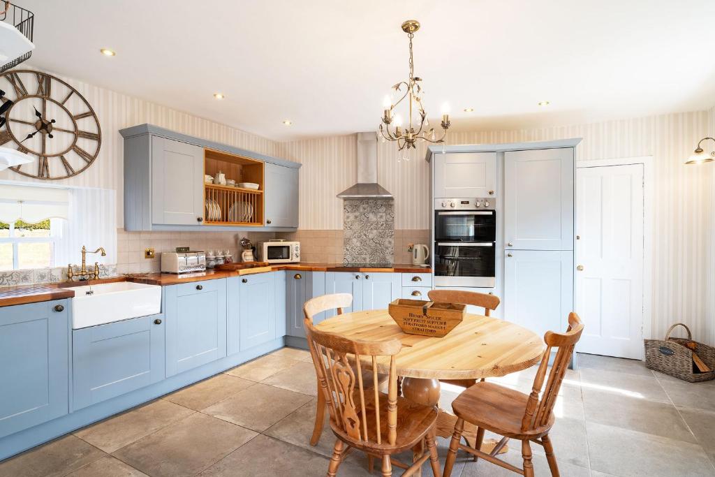 cocina con armarios azules y mesa de madera en Thrums Cottage en Kirriemuir