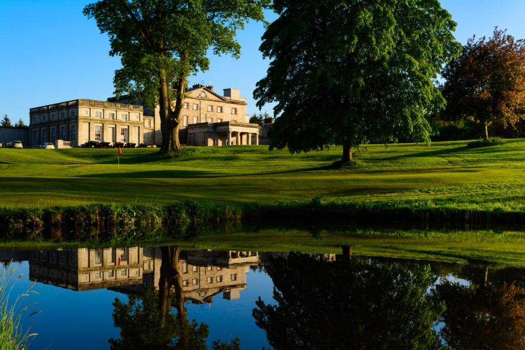 een huis op een golfbaan met een reflectie in het water bij Cally Palace Hotel & Golf Course in Gatehouse of Fleet