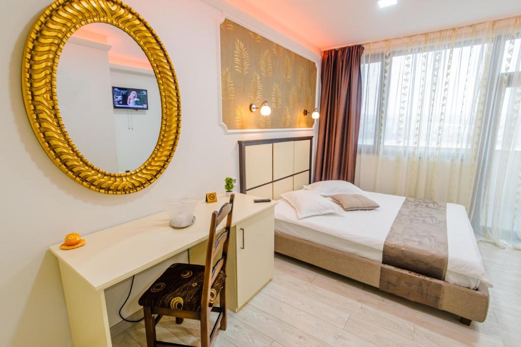 1 dormitorio con cama, escritorio y espejo en Hostel Parc en Fălticeni