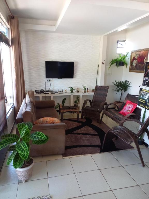 een woonkamer met een bank en stoelen en een flatscreen-tv bij Pousada Adorno in Colinas Do Sul