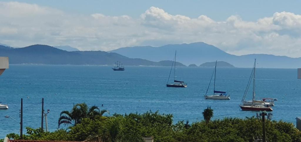 un grupo de barcos en el agua con montañas en el fondo en Jurerê Summer - Vista pro Mar - Ultra Internet 600 Mega, en Florianópolis