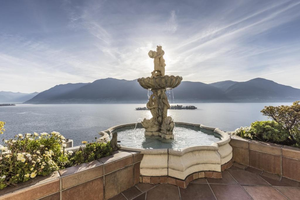 uma fonte na frente de um corpo de água em Boutique Hotel La Rocca em Ronco sopra Ascona