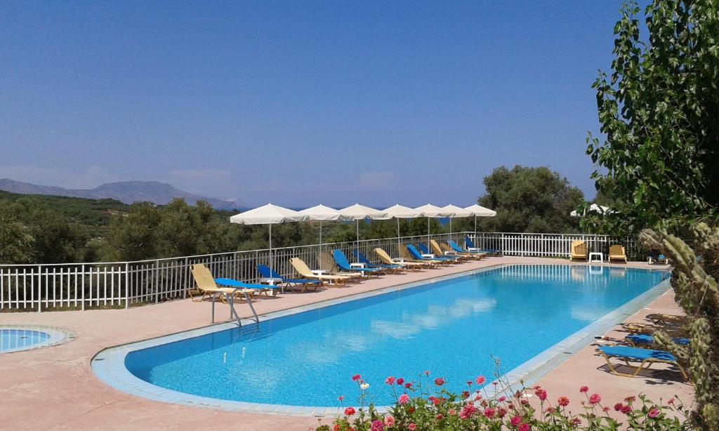 una gran piscina con sillas y sombrillas en Calamon Apartments, en Episkopí- Rethimno