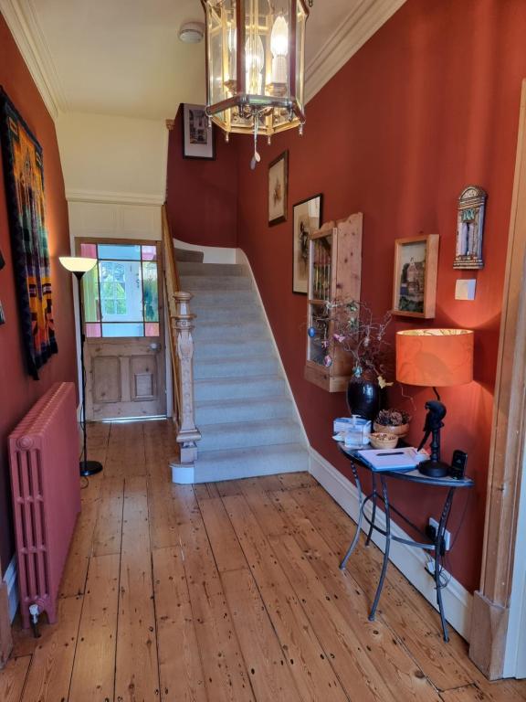 a hallway with orange walls and stairs with a chandelier at Alma House Bed and Breakfast in Newbury