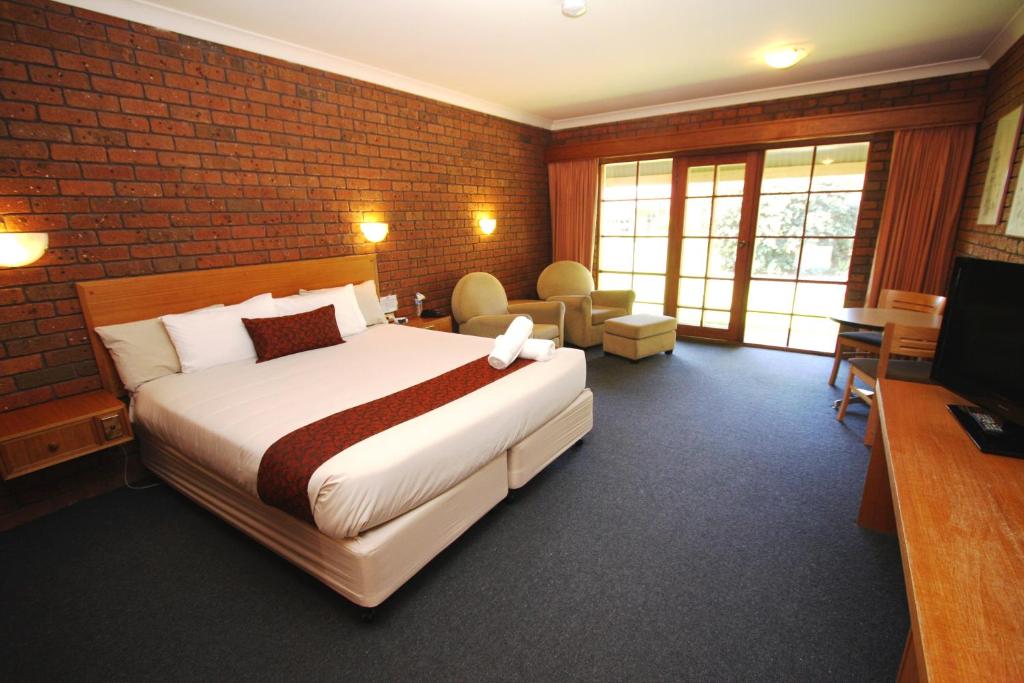 ein Schlafzimmer mit einem großen Bett und einer Ziegelwand in der Unterkunft Grange Burn Motel in Hamilton