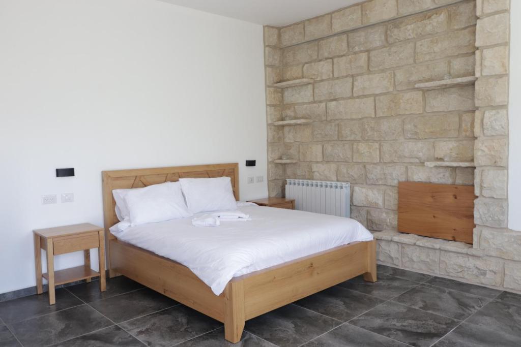 a bedroom with a bed and a brick wall at Oriental Nature in Majdal Shams
