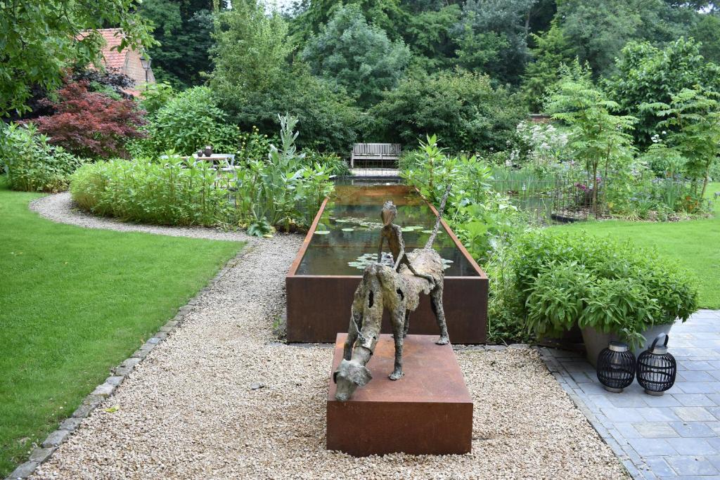 posąg siedzący na ławce w ogrodzie w obiekcie B&B Pastorie van Merkem w mieście Merkem