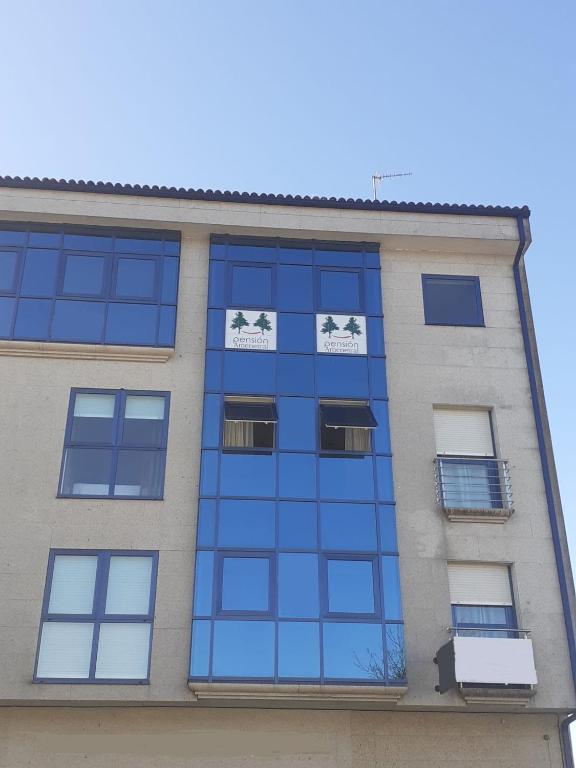 een hoog gebouw met blauwe glazen ramen bij Pension Ameneiral in O Pedrouzo