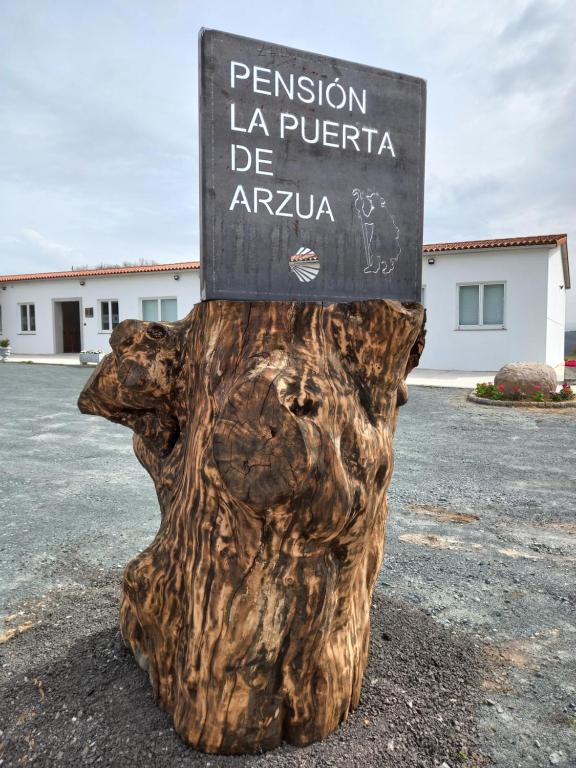 una señal sentada en la parte superior de un tronco de árbol en LA PUERTA DE ARZÚA en Arzúa