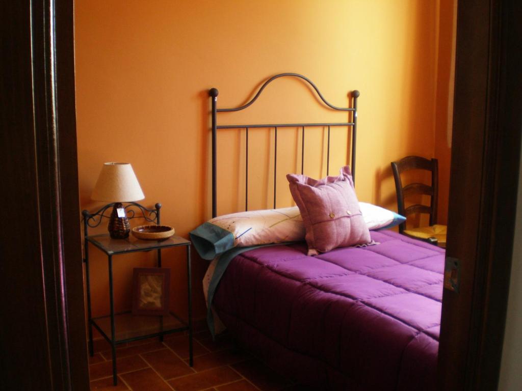 sypialnia z łóżkiem z fioletową pościelą i lampką w obiekcie Apartamentos Rurales El Cañuelo de Carcabuey w mieście Carcabuey
