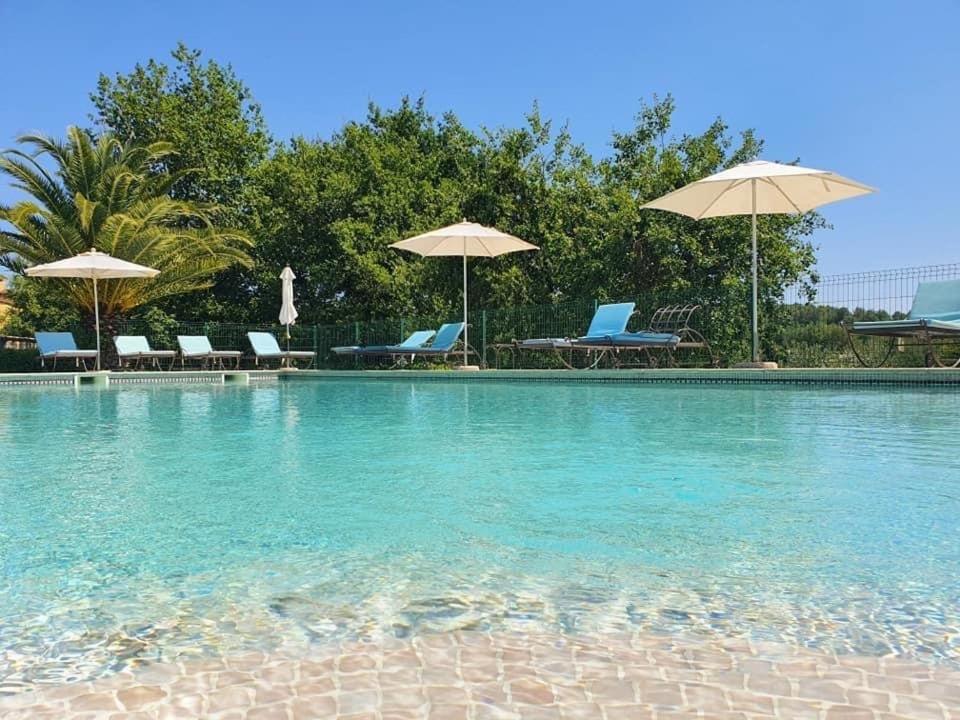 a swimming pool with chairs and umbrellas at La Résidence du Moulin in Tourrettes-sur-Loup