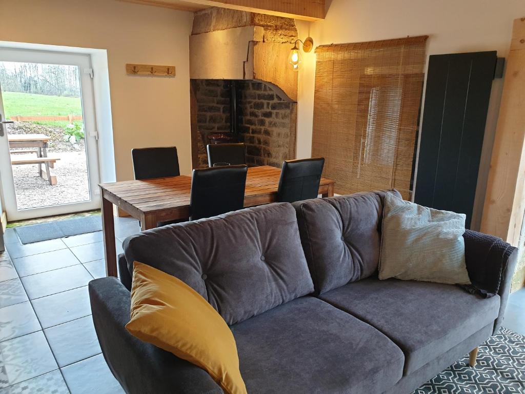 a living room with a couch and a dining table at Les Vergers d'Epona "Fougerolles Haute-Saône" in Fougerolles
