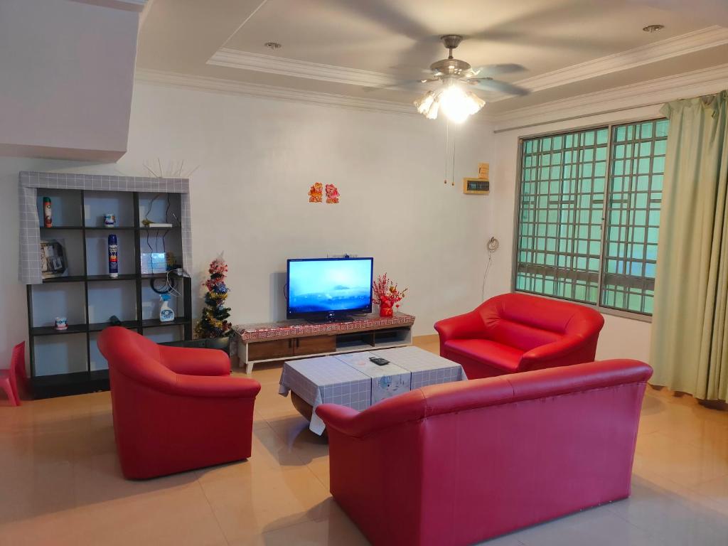 salon z 2 czerwonymi krzesłami i telewizorem w obiekcie NH Homestay Sibu w mieście Sibu