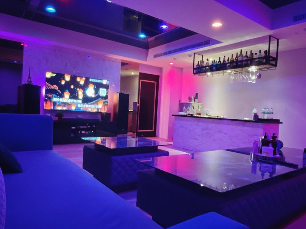 una sala de estar con un bar con iluminación púrpura en Felicity Business Hotel en Taichung