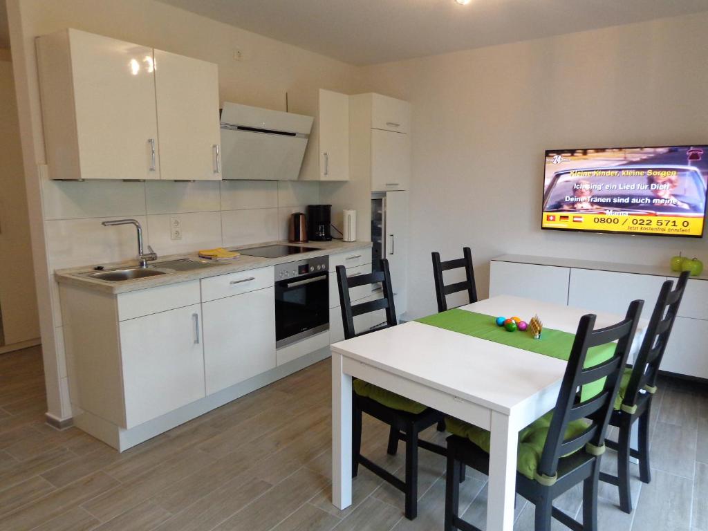 a kitchen with a white table and chairs in a room at Ostfrieslands Perle Ferienwohnung an der Nordseeküste, Sauna, Terrasse, Garten, ruhige Lage, WLAN in Norden