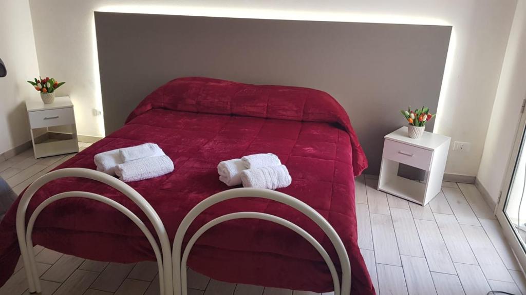 1 dormitorio con 1 cama roja y 2 toallas en B & B Da Rosa, en Petrosino