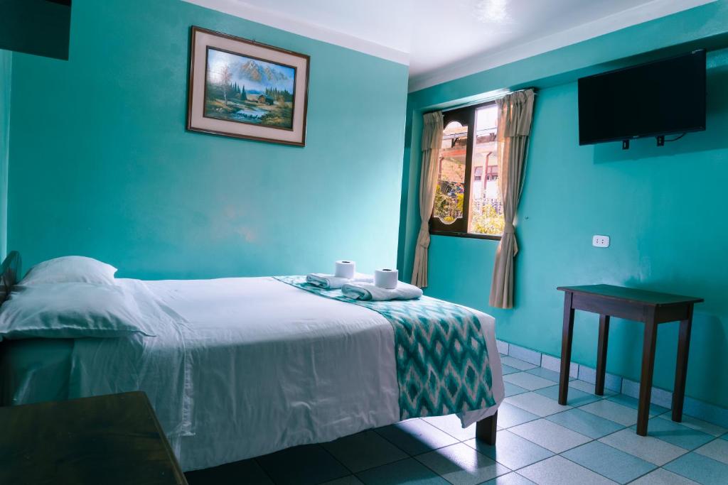 1 dormitorio con paredes azules, 1 cama y 1 mesa en ALPA KASA CHACHAPOYAS, en Chachapoyas