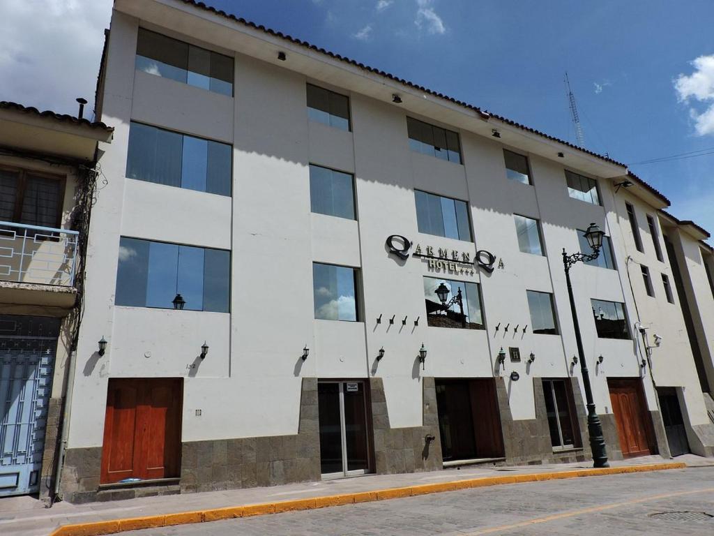 a large white building with windows on a street at Qarmenqa Hotel in Cusco