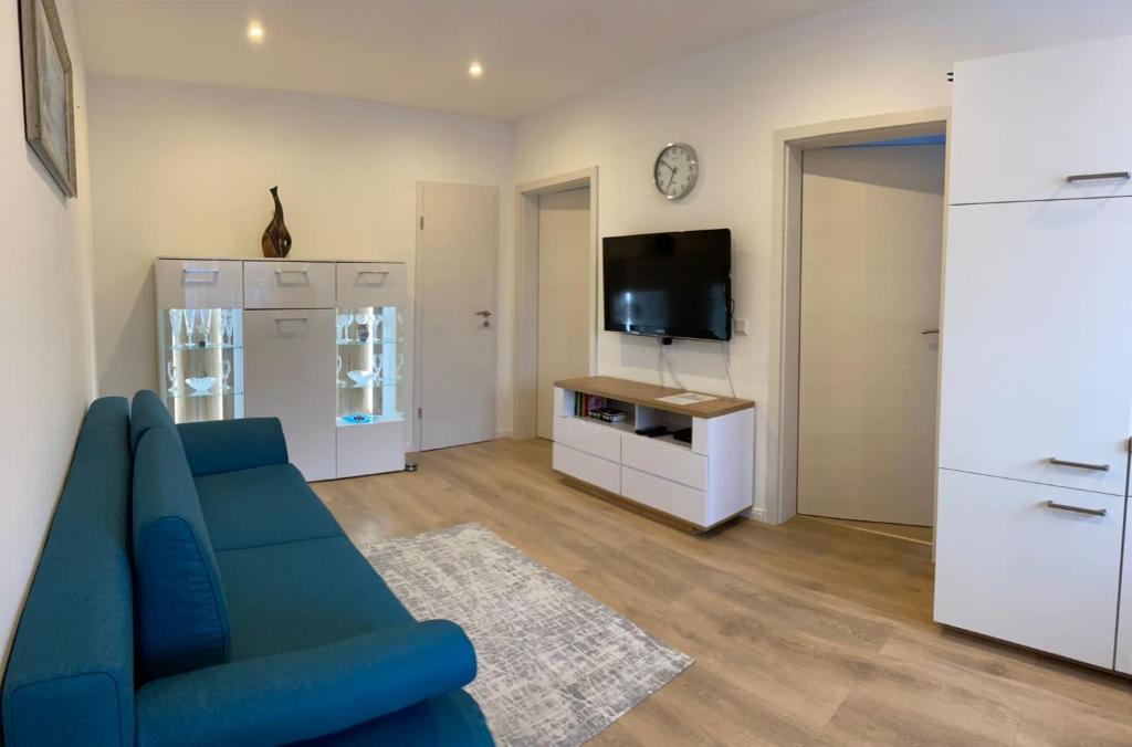 uma sala de estar com um sofá azul e uma televisão em FERIENWOHNUNG BAD DRIBURG em Bad Driburg