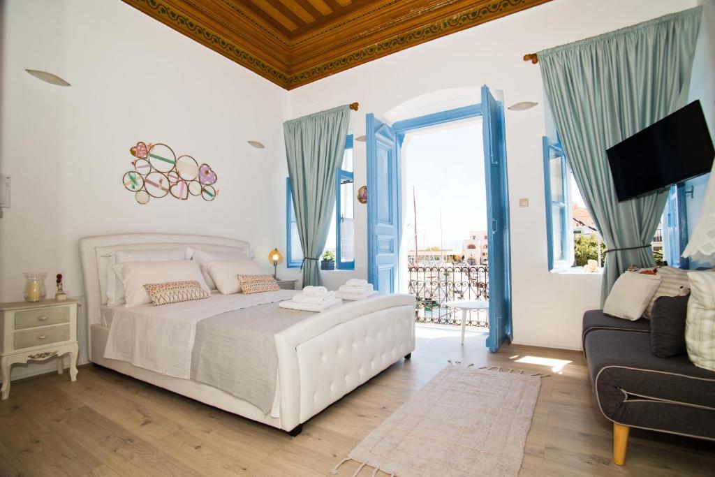 a white bedroom with a bed and a couch at spongkalyA apartment I in Kalymnos