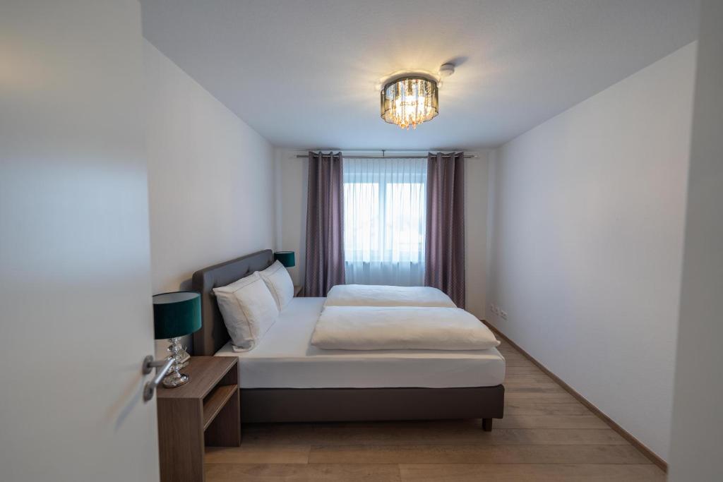 a small bedroom with a bed and a chandelier at City Wohnung Relax 3 klimatisiert in Friedrichshafen