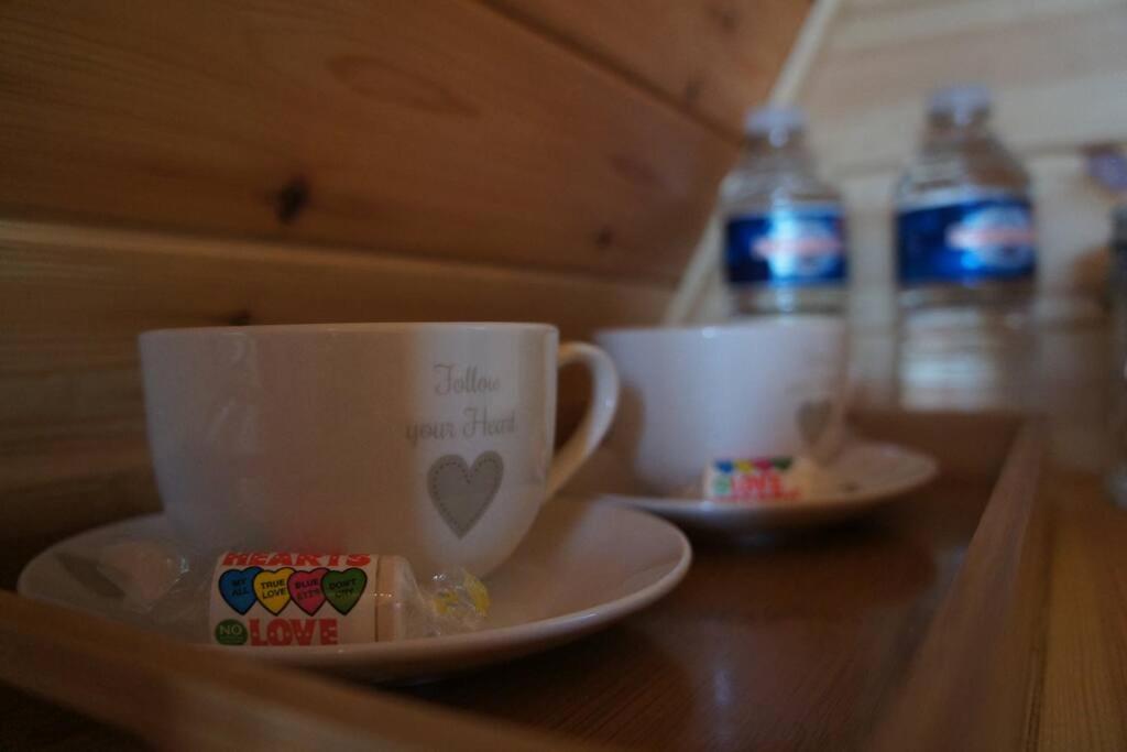 トーントンにあるRiverside Retreatのテーブルの上にカップとソーサーとボトル入り飲料水2本