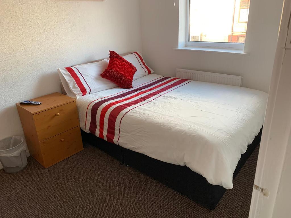 a bedroom with a bed with a red pillow on it at Starlight Self Service Accommodation in Leigh