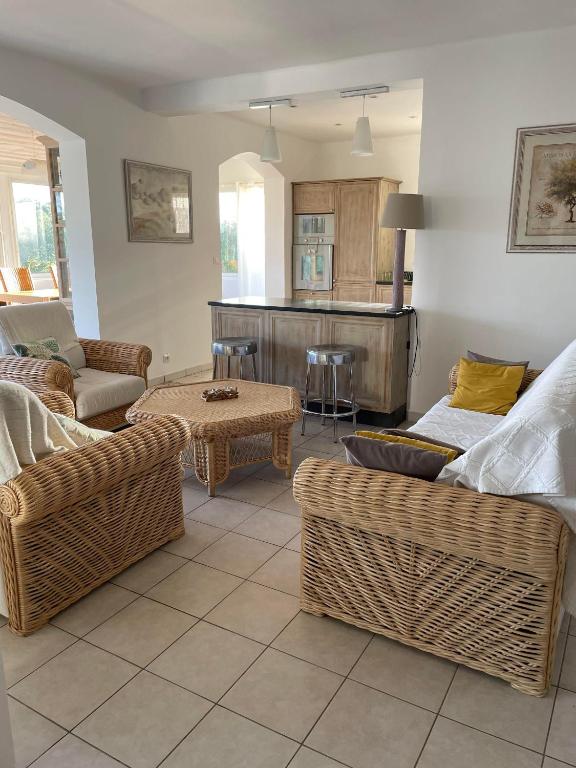 a living room with wicker furniture and a kitchen at Hotel Villa Maya in Saint-Tropez