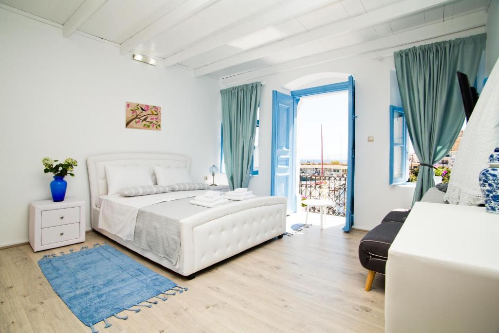 a white bedroom with a white bed and a window at spongkalyA apartment II in Kalymnos