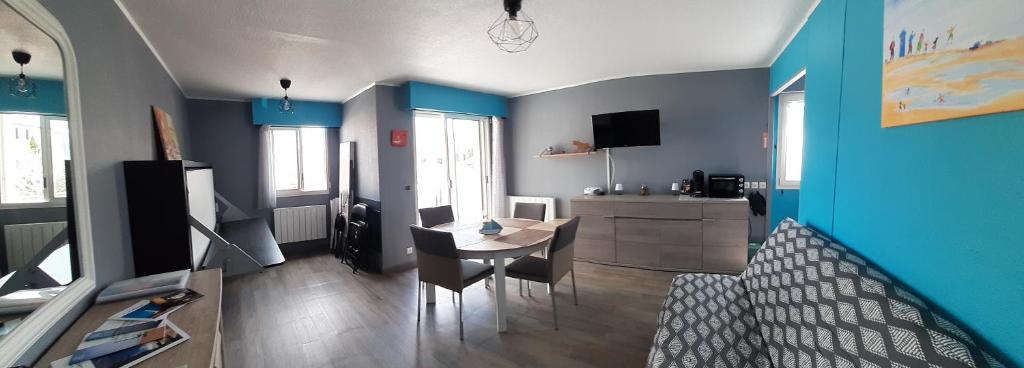 a living room with blue walls and a table and chairs at Le Petit Bleu de Didonne 28m2 150 m de la plage avec balcon in Saint-Georges-de-Didonne