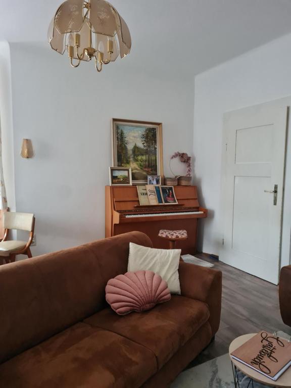 a living room with a brown couch and a piano at Ferienhaus Hildegard & Horst - Urlaub im Herzen des Fichtelgebirge in Hohenberg an der Eger