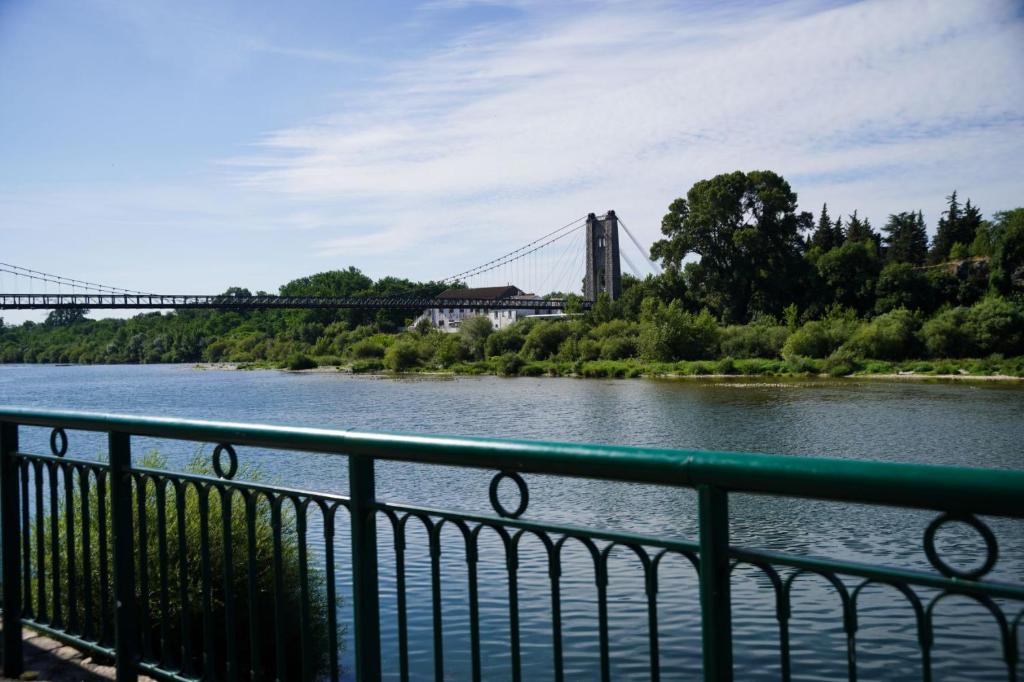 a bridge over a river with a green railing at Les Verveines in Saint-Martin-dʼArdèche
